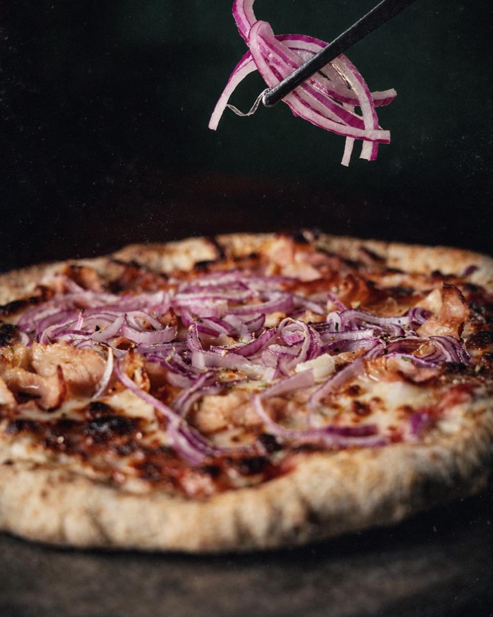 Pizza al horno con cebolla morada cayendo encima